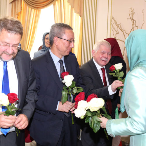 Maryam Rajavi offers flowers to political dignitaries at the celebration of the Relocation of Camp Liberty residents